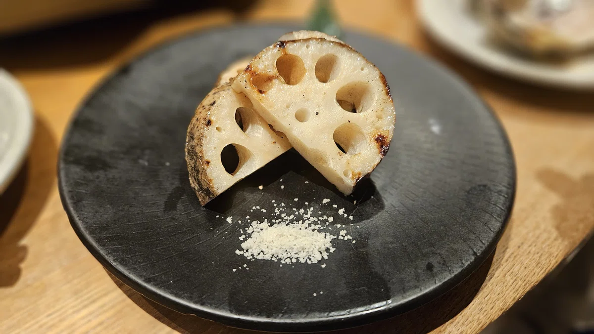 厚切りのれんこんを香ばしく焼き、トリュフ塩を添えた一皿。断面の穴が美しい焼き野菜。