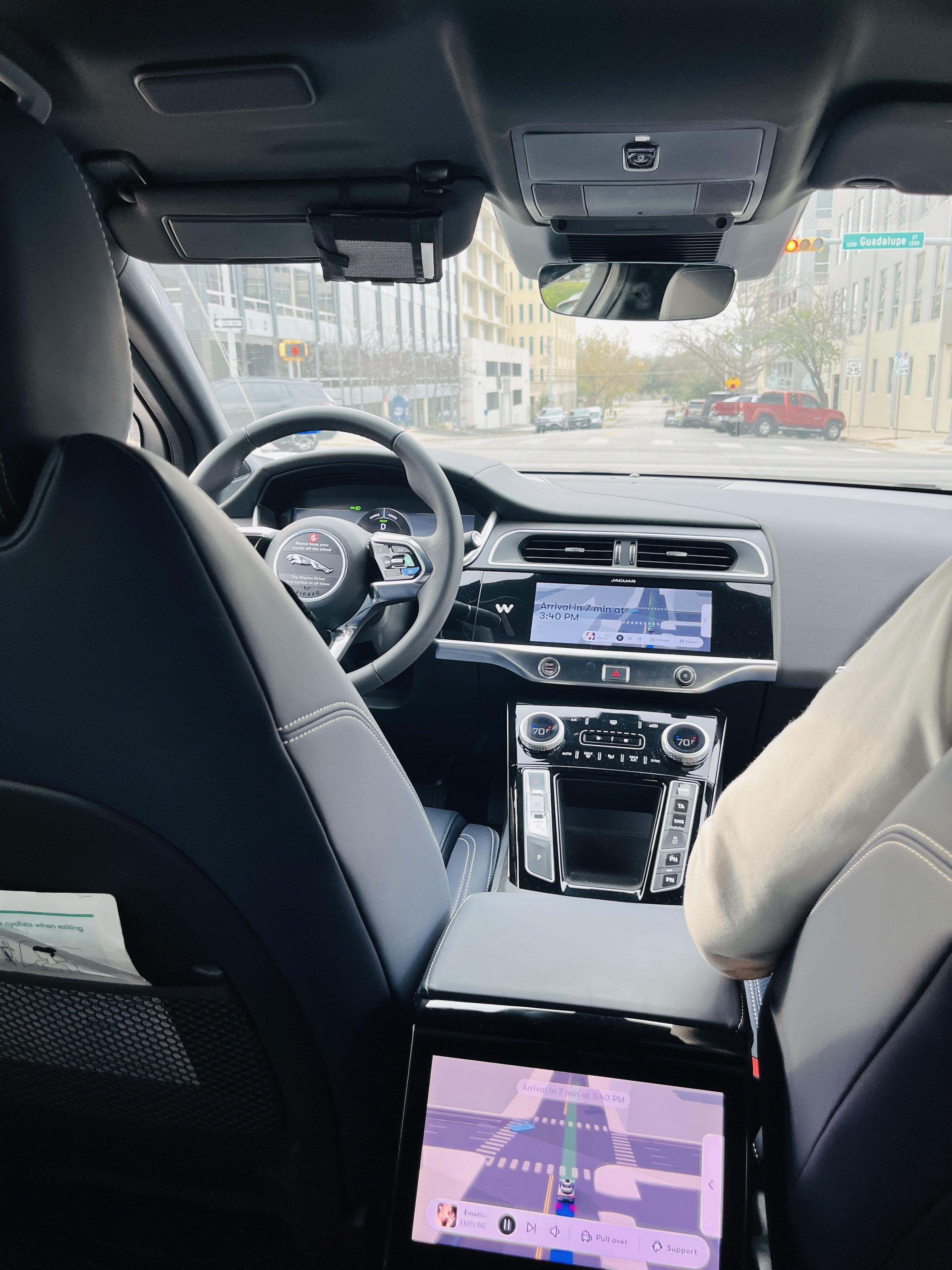 From inside a Waymo car that temporarily stops at an intersection with a red light. There is a button to stop the car in case of an emergency.