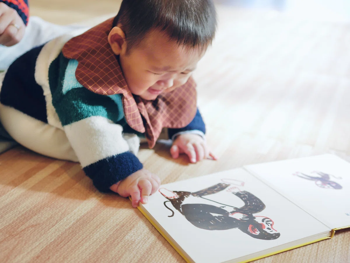 絵本のページがうまくめくれず泣き出す生後5か月の男の子