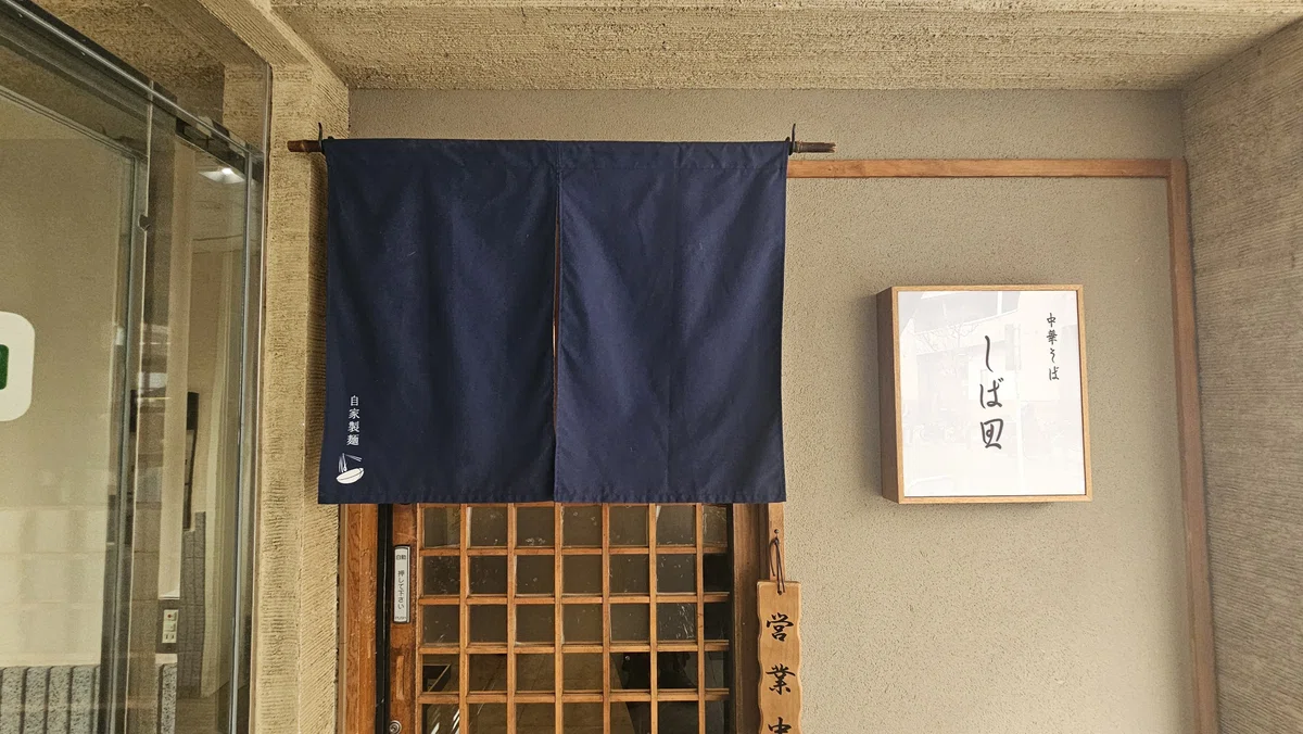 東京・仙川の人気ラーメン店「しば田」の外観。暖簾がかかる落ち着いた佇まいの入口。