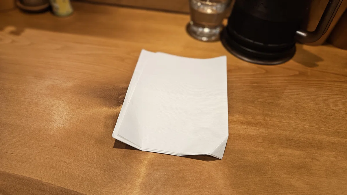 店内に置かれた白い紙エプロン。食券機横から自由に取れる仕様。