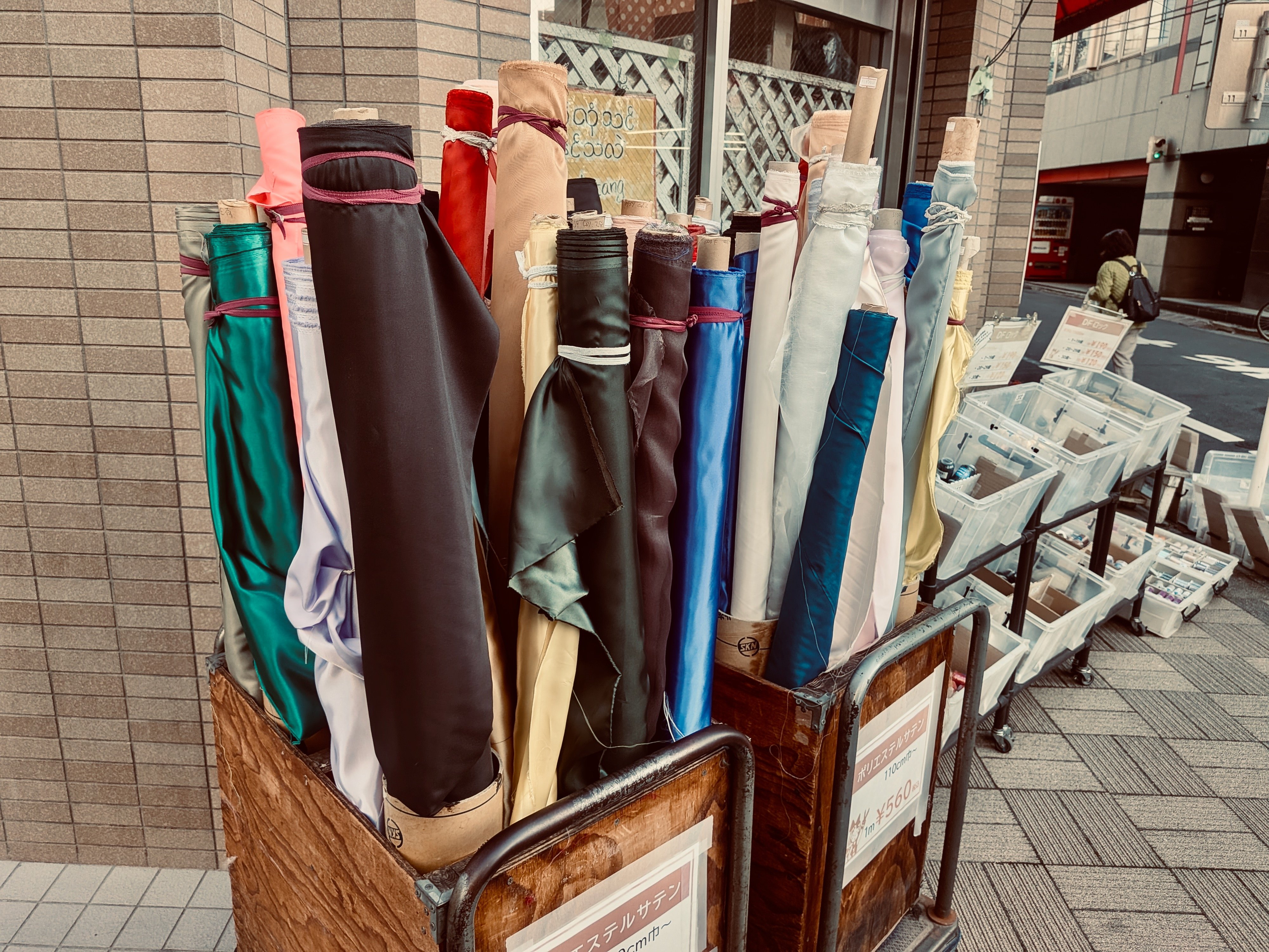 店先に生地のロールがたてて売られている。黒、ブラウン、ブルーなどカラフル