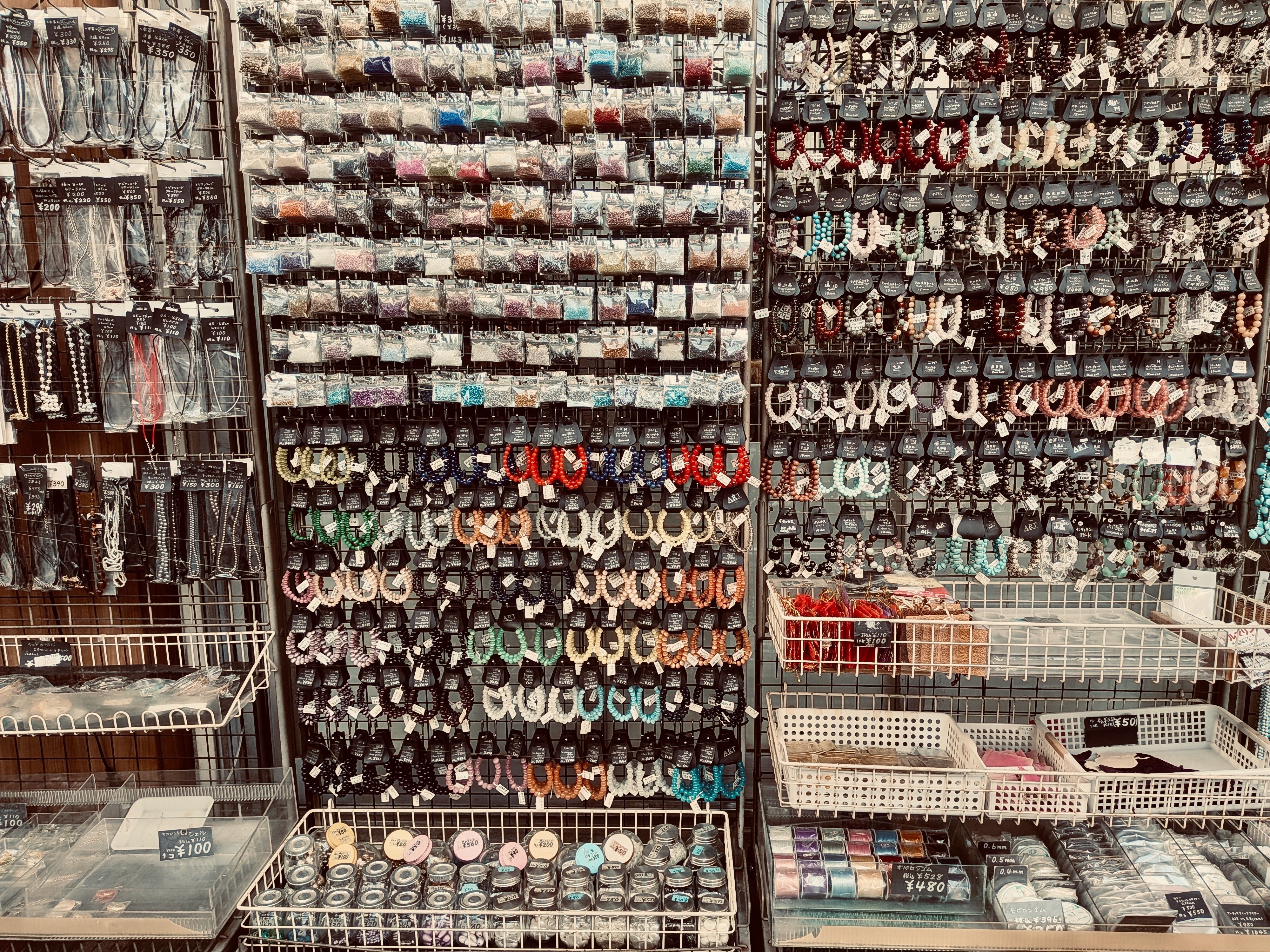 ビーズや手芸アクセサリーの棚。膨大なつぶつぶが壁にかけられている