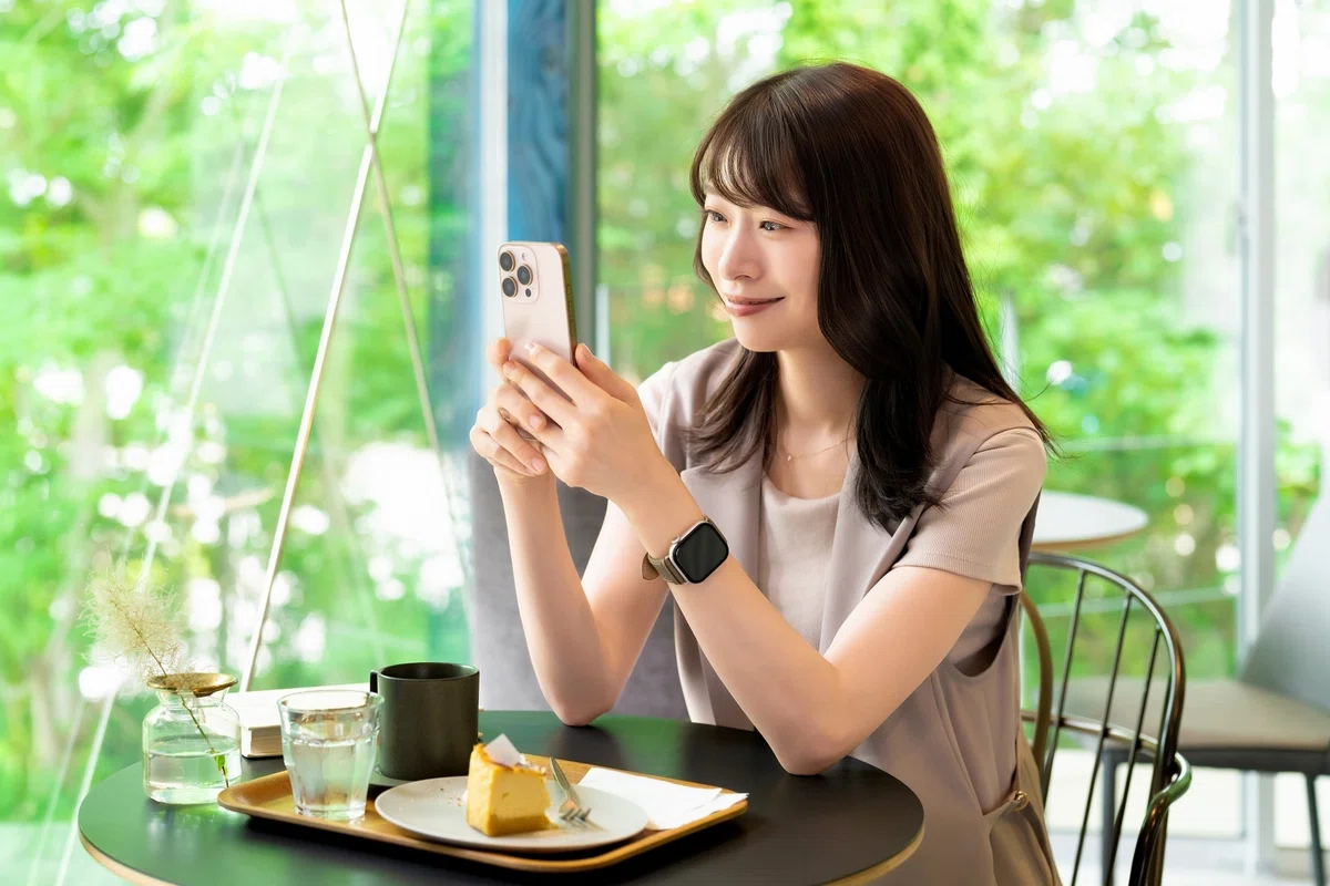 iPhoneで調べているカフェの女性