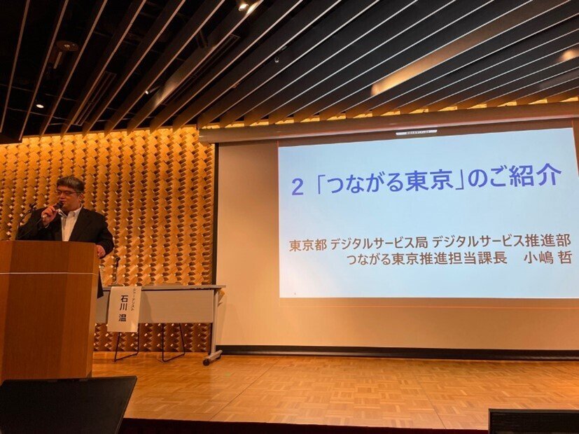 説明会にて、投影スクリーンを用いながら「つながる東京」の取り組みについて紹介する東京都職員。