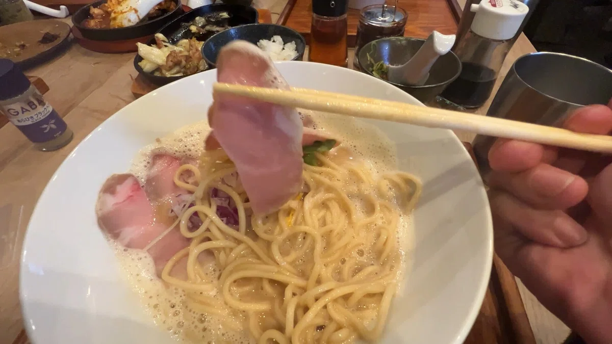 鶏白湯ラーメンの美しい全貌!きれいなピンク色のお肉と、食欲をそそる丸ごと味玉。見ているだけでお腹が空いてきます。