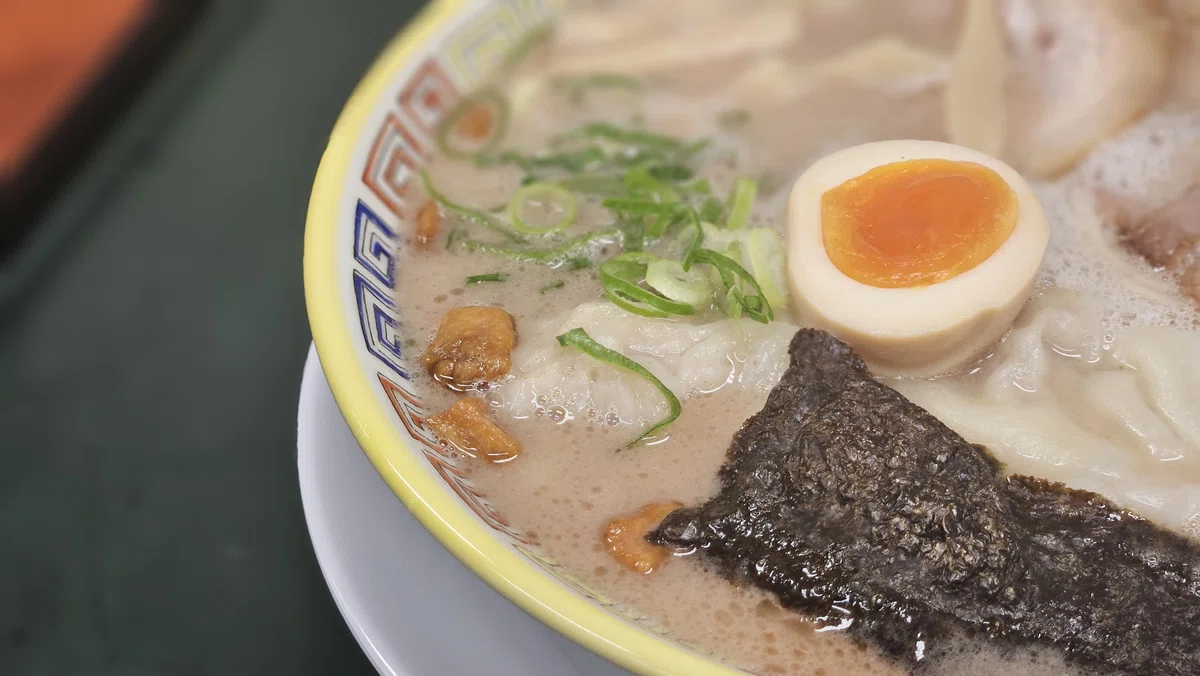 豚脂の揚げ玉「カリカリ」と紅ショウガが乗ったラーメンのアップ写真。食感のアクセントが特徴。