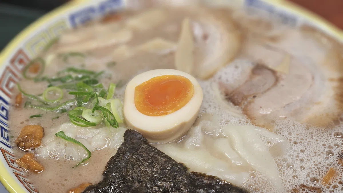 ワンタンと半熟卵、チャーシューが乗ったラーメンのアップ。とろける卵が印象的。