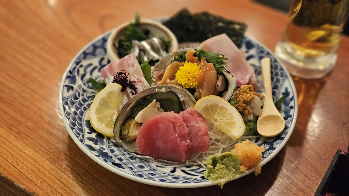 まぐろ、貝、白身、雲丹などが美しく盛られた豪華な一皿。レモンと大葉、わさびが添えられている