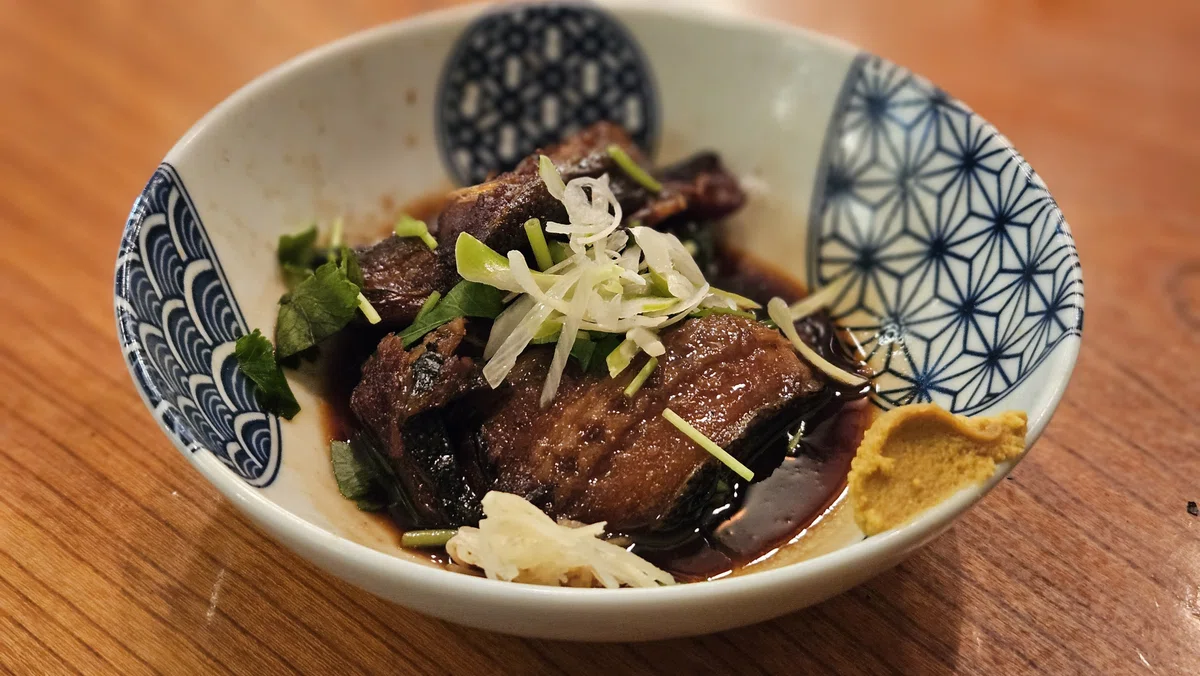 甘辛いタレでじっくり煮た魚。ネギと薬味がアクセント