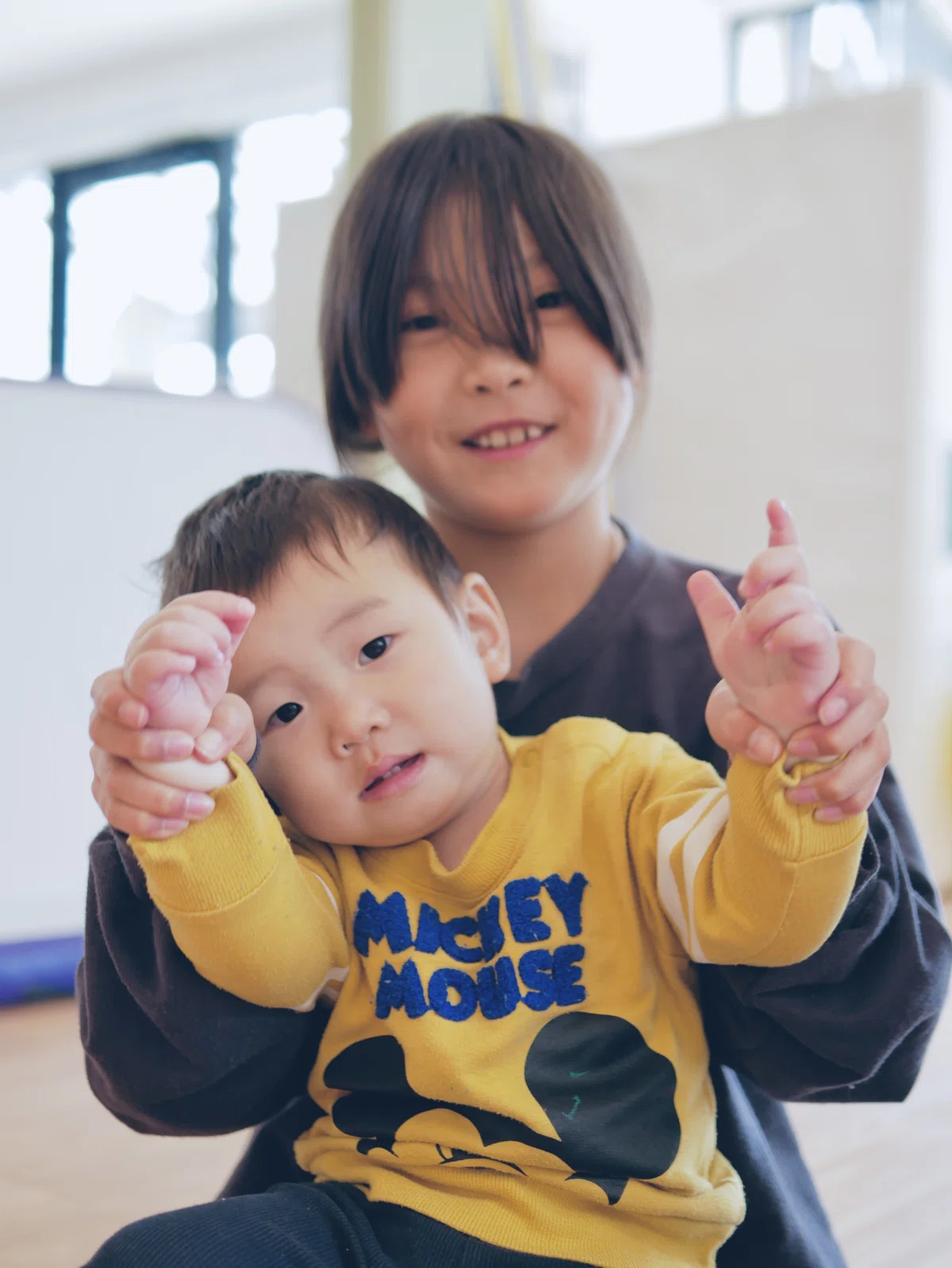 1歳の弟くんの手をとって、サインの練習につきあう小学生のお姉ちゃん