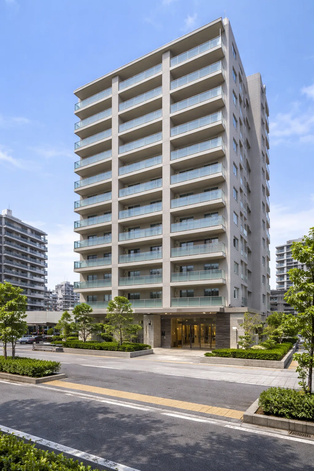 東環再開発帯に建つシティコート東環の昼間の外観。ベージュ系の外壁とガラス手すりのバルコニーが並ぶ地上12階建ての高層マンションで、前面には広い歩道、植栽帯、車寄せ、明るいエントランスが見える。