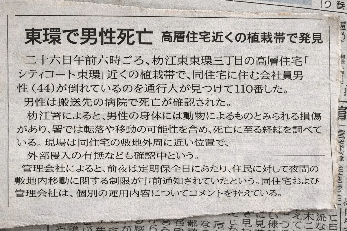 地方紙の紙面を切り抜いて撮影した小さな記事。見出しは「東環で男性死亡　高層住宅近くの植栽帯で発見」で、シティコート東環近くで住民男性が死亡したこと、動物によるものとみられる損傷、前夜が定期保全日であったことが本文に記されている。