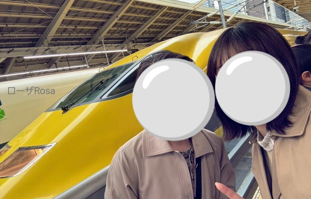ドクターイエローの前で記念撮影する母子の画像