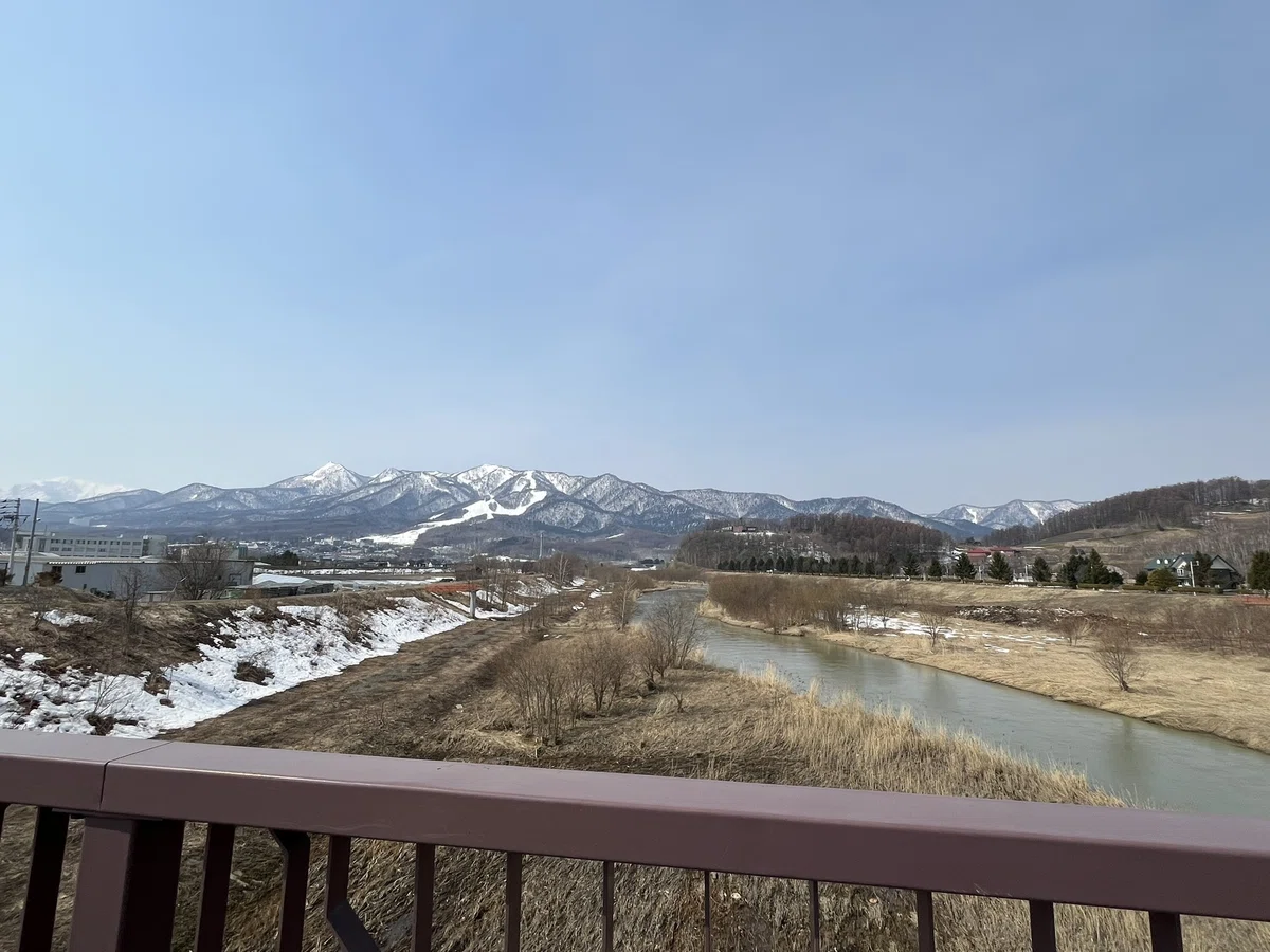 シャトーふらの橋の向こうに雪が残る山々が見える