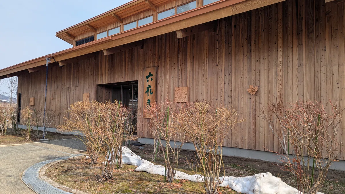 木造平屋のカンパーナ六花亭外観。手前に冬囲いされたバラが並んでいる。