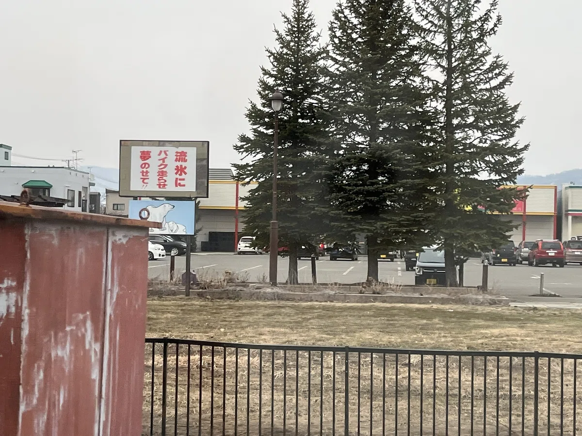 白い看板に、赤いペンキで「流氷にバイク走らせ夢のせて」と書かれている。