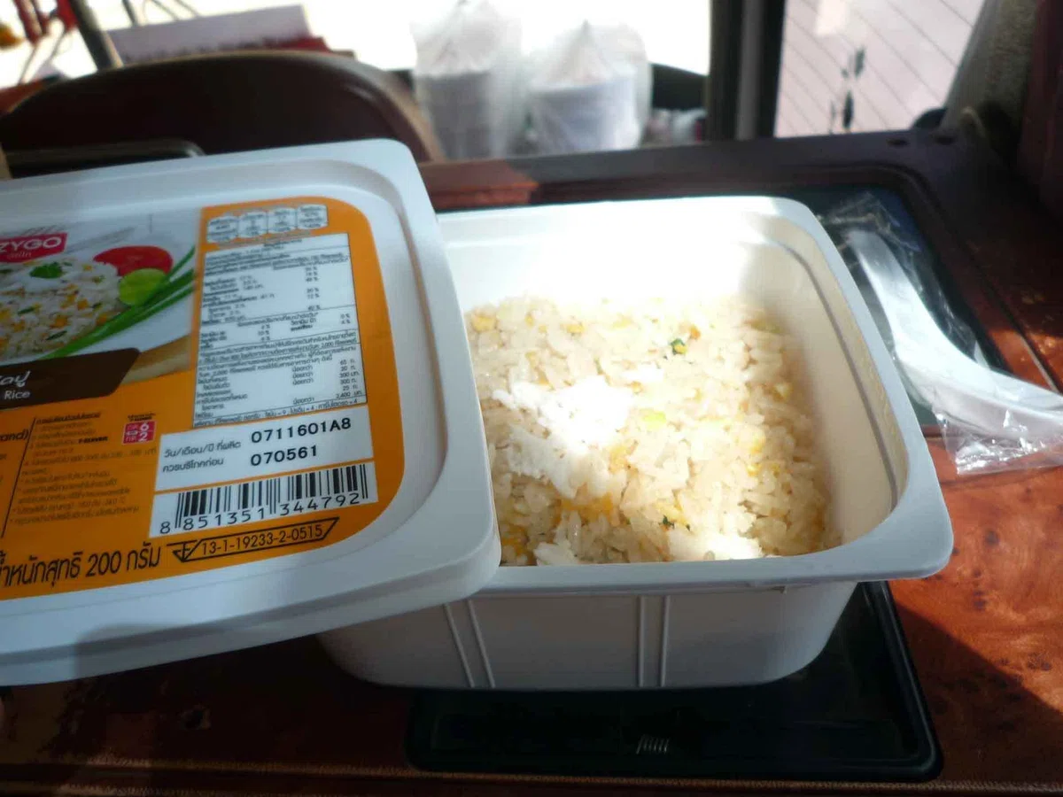 バス車内のテーブルに、ふたを開けた弁当が置かれている。容器の中にはご飯が入っている。