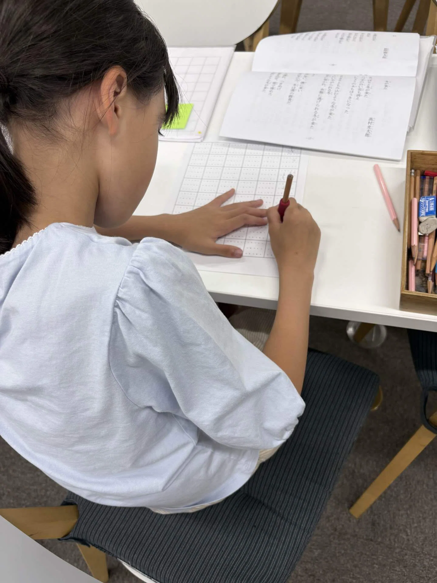 机に向かい硬筆の課題へ集中する子ども