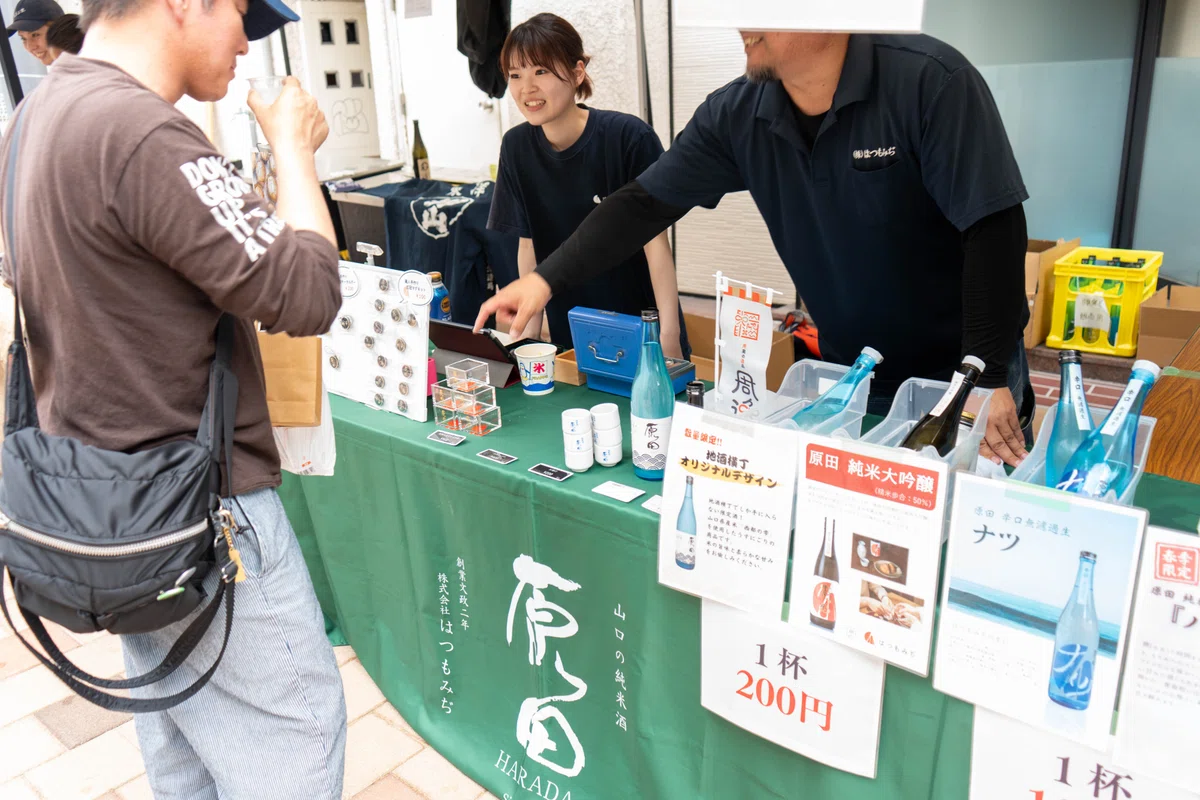 ブースで日本酒を受け取り口に含む男性