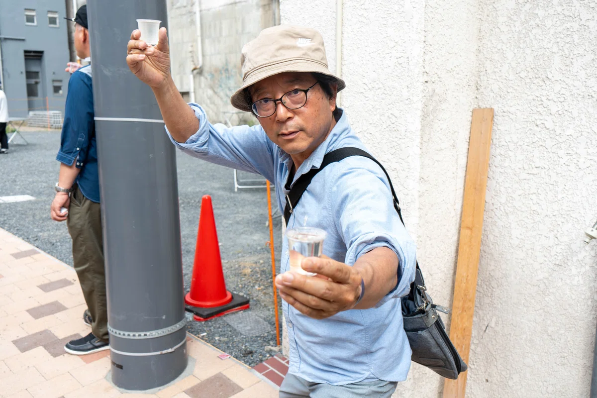 両手にお猪口を持ち、ポーズをとる男性