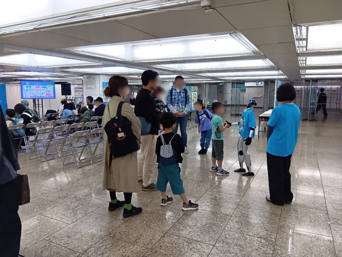 ヒューマノイドロボットと来場者のふれあいの様子。ロボットと男の子が握手している。