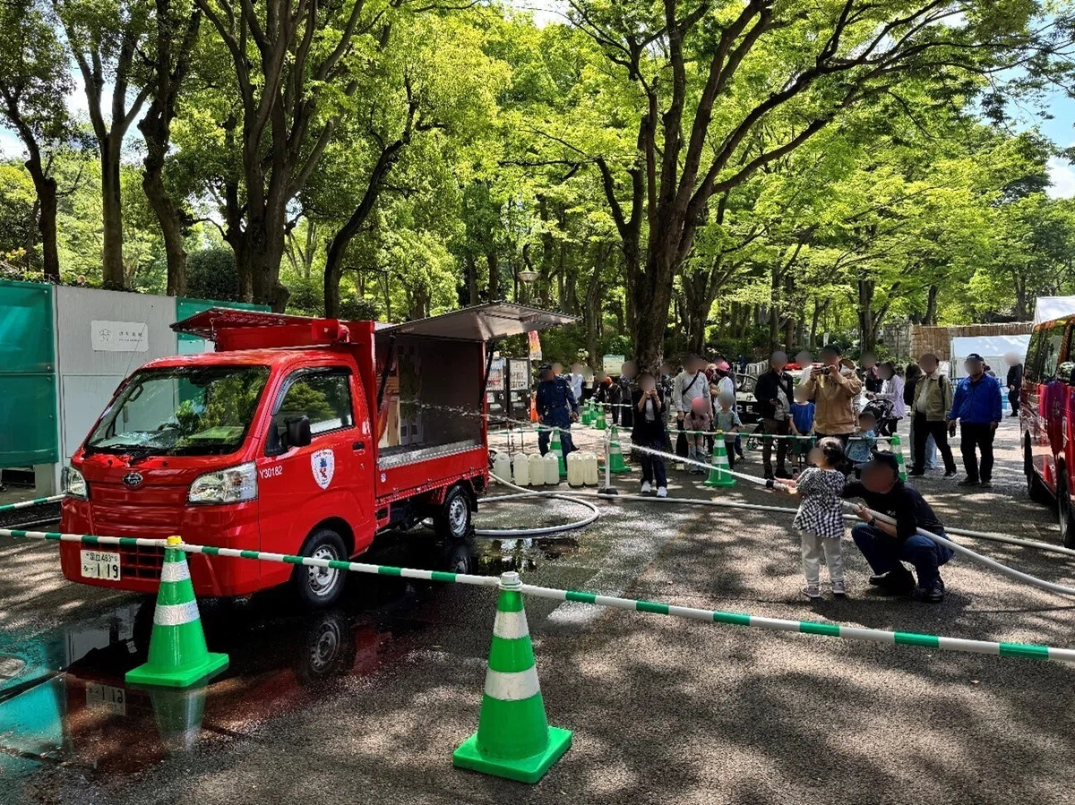 模擬防災訓練の様子。女の子が火災に見立てた絵に向かって、ホースを使って水をかけている。