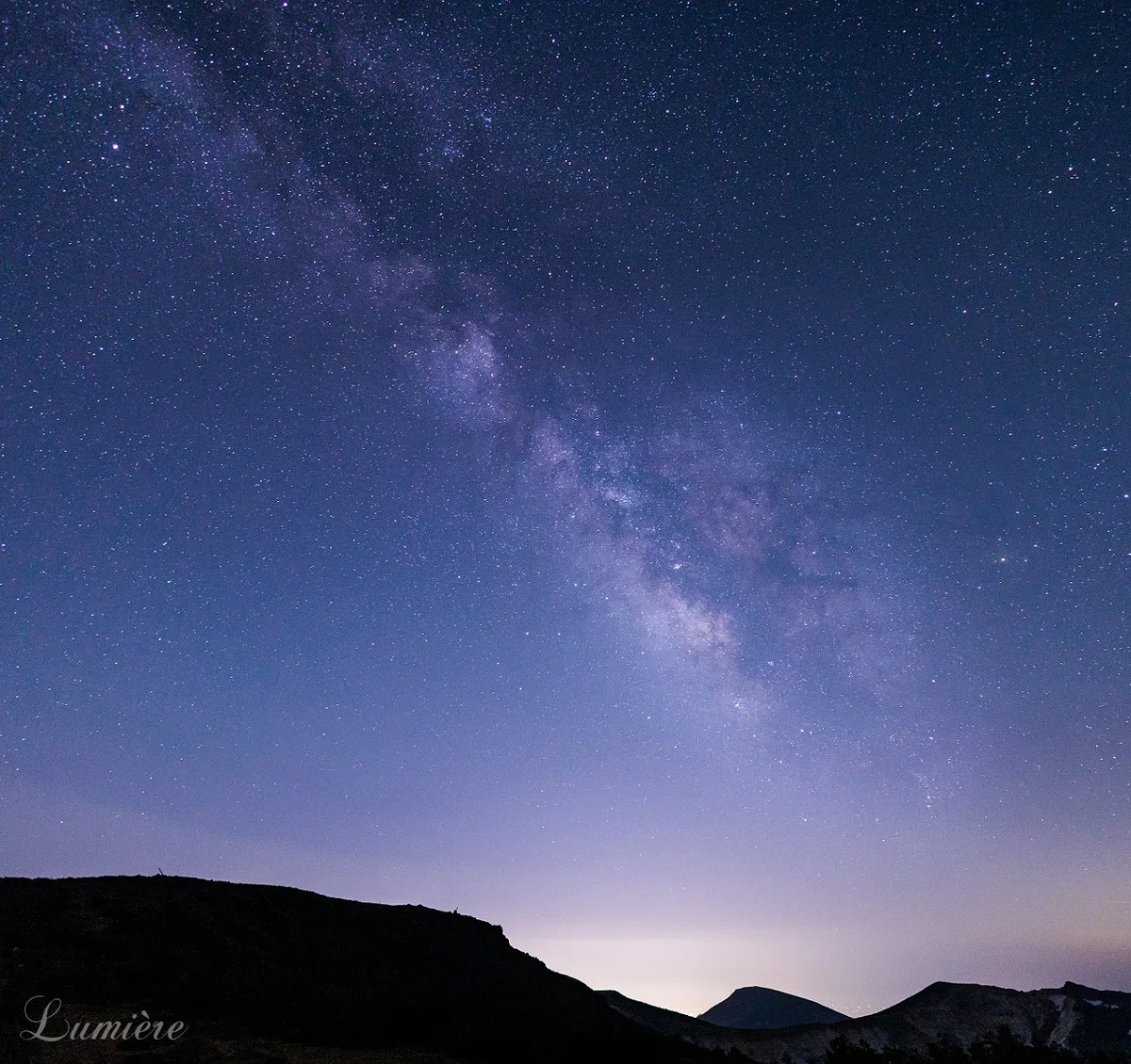 美しい青い夜空に紫の銀河が横切り、満点の星がきらめいている写真