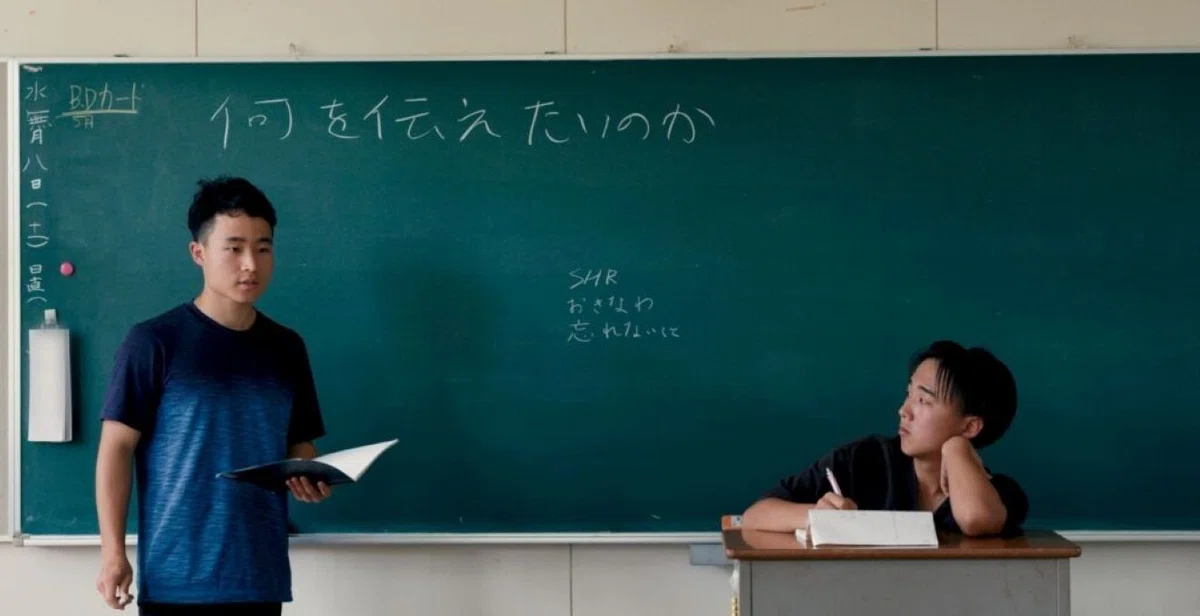 劇中より黒板の前で話す生徒たち