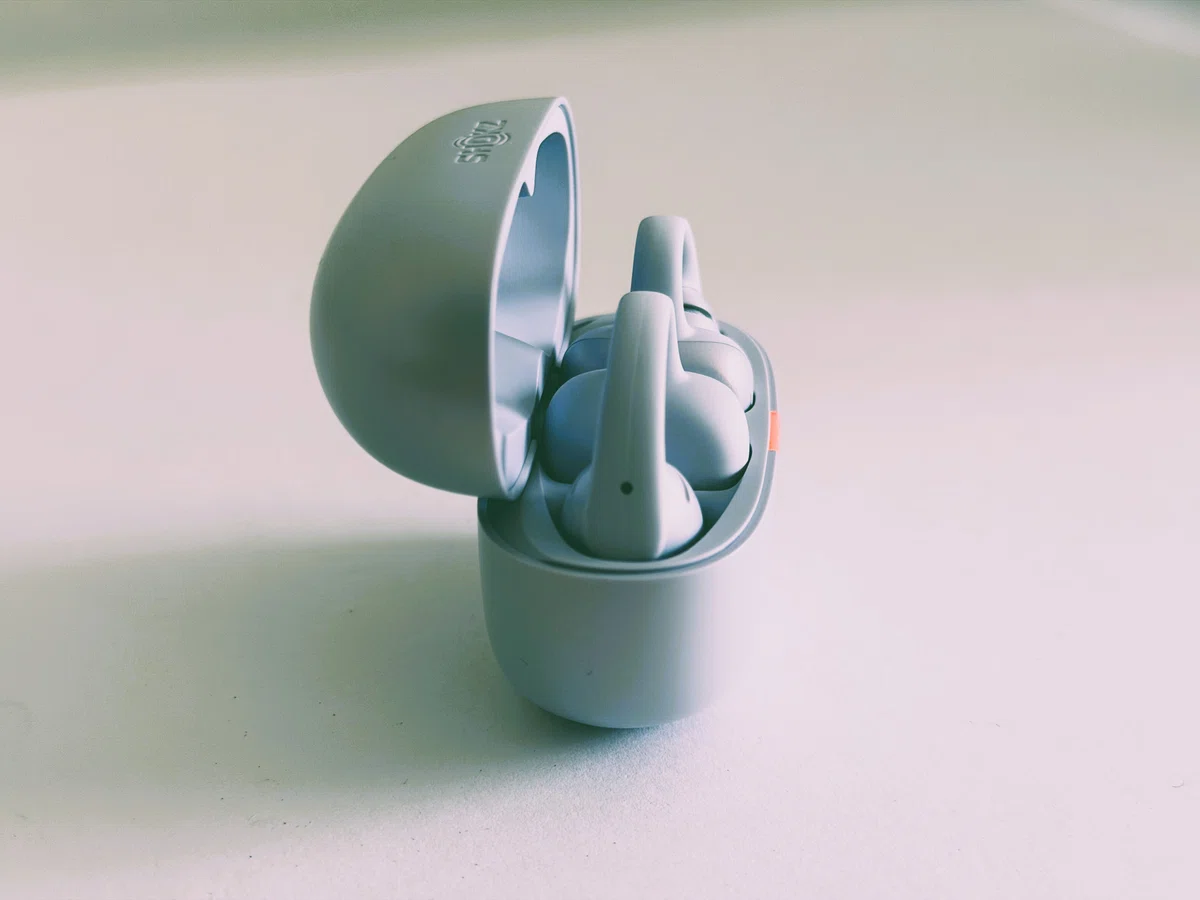 Shokz OpenDots Air デイブレイクパープル。耳に挟んで使うイヤーカフ型イヤホンのケースを開けた外観写真。