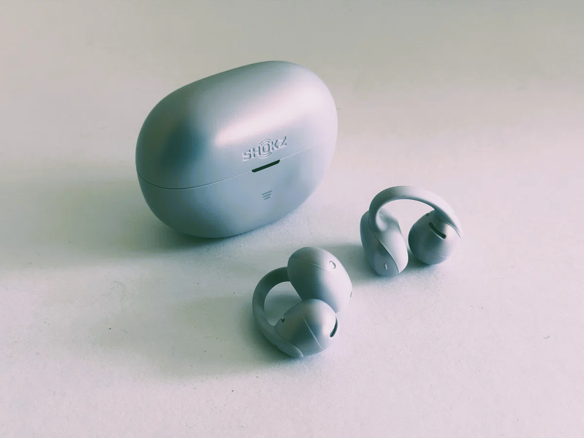 Shokz OpenDots Air デイブレイクパープル。耳に挟んで使うイヤーカフ型イヤホンとケースの外観写真。