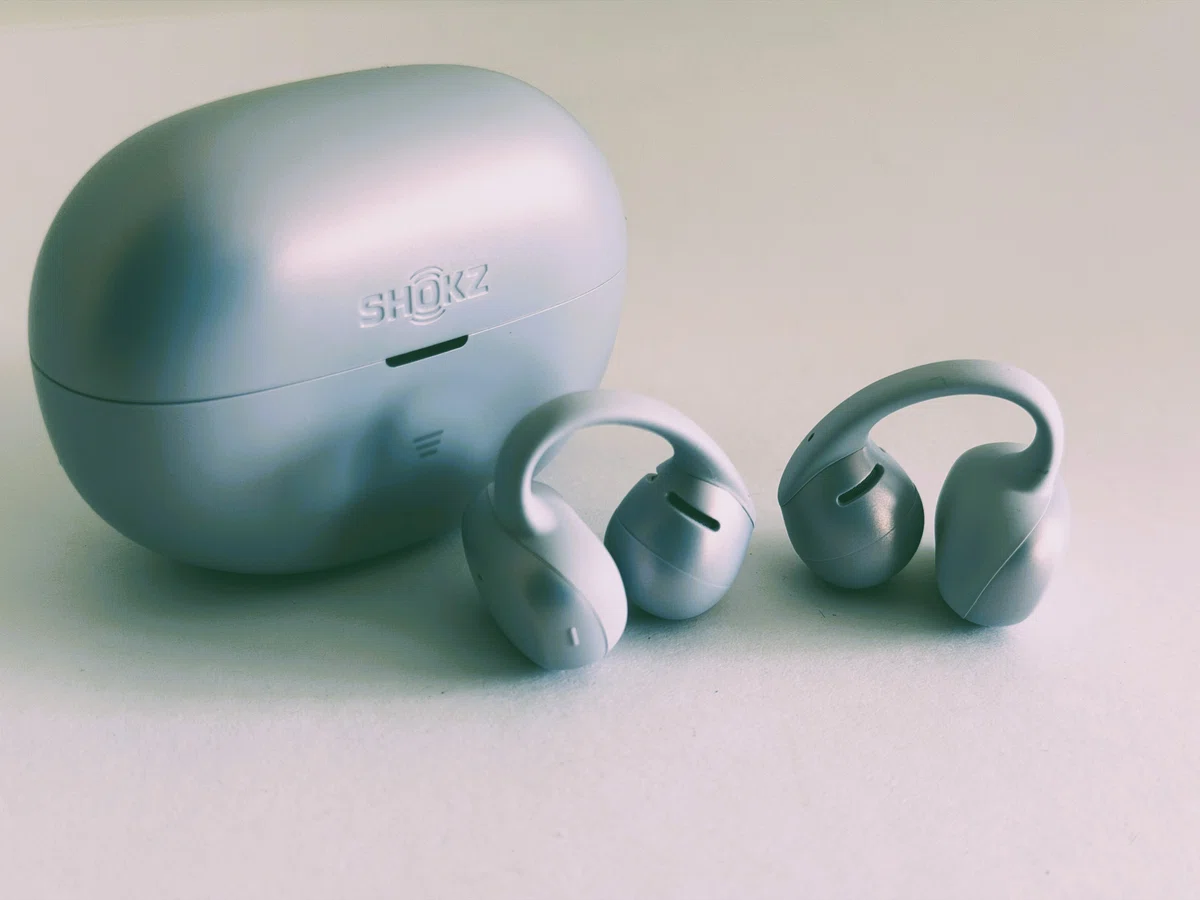 Shokz OpenDots Air デイブレイクパープル。耳に挟んで使うイヤーカフ型イヤホンとケースの外観写真。