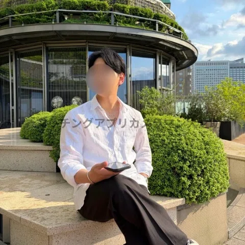 男性が日比谷ミッドタウンの屋上テラスのベンチに座っている姿を写したマッチングアプリ用のプロフィール写真