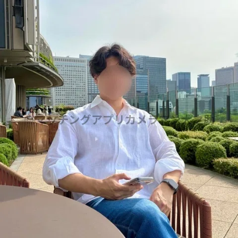 男性が日比谷ミッドタウンの屋上テラスの椅子に座っている姿を写したマッチングアプリ用のプロフィール写真