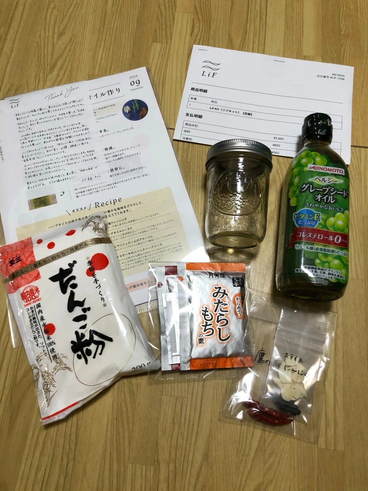 LiFの9月キットの中身。グレープシードオイル、瓶、にんにく・唐辛子、みたらし団子の素、だんご粉、手書きのレシピが並ぶ