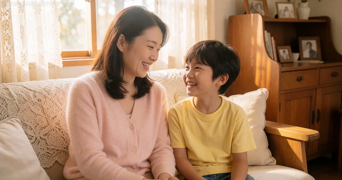 明るいリビングのソファで顔を見合わせて大笑いする母親と小さな男の子の画像