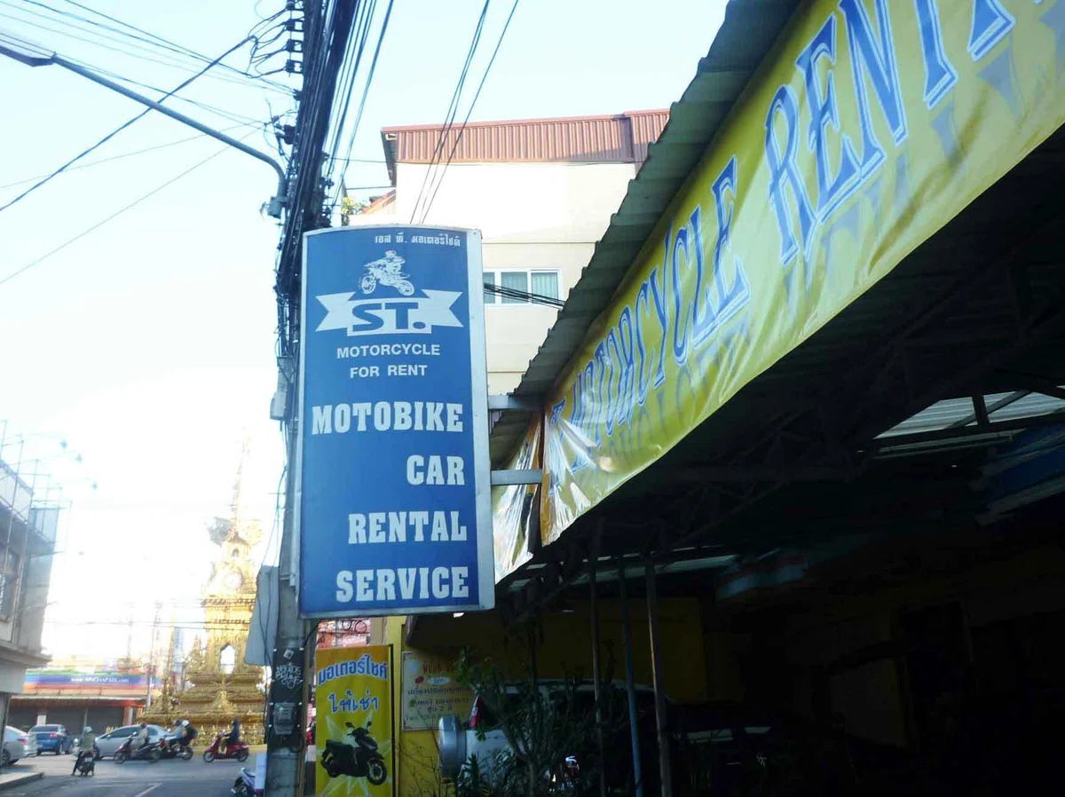 「MOTORCYCLE FOR RENT」の青い看板が掲げられた通り沿いのレンタル店