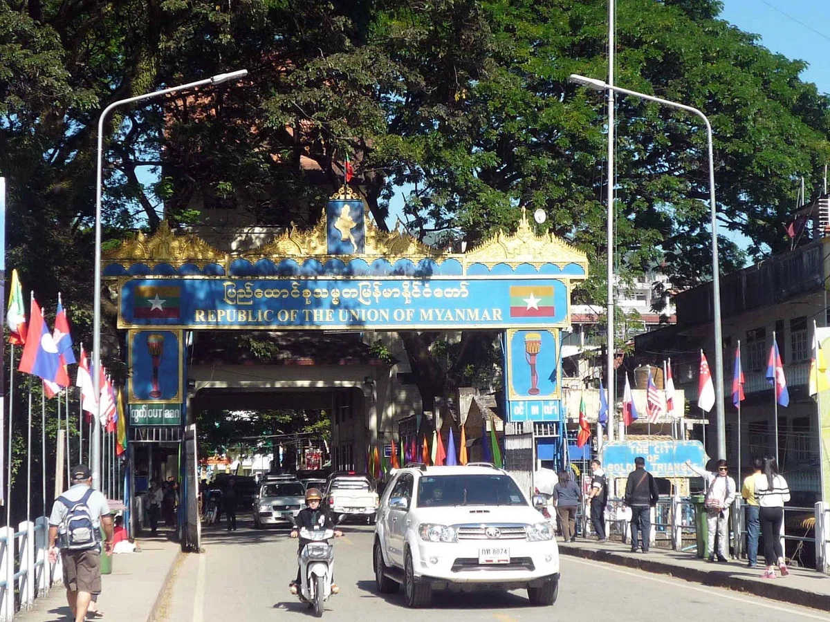 「REPUBLIC OF THE UNION OF MYANMAR」と書かれた青と金のゲートを、車やバイクが通過している