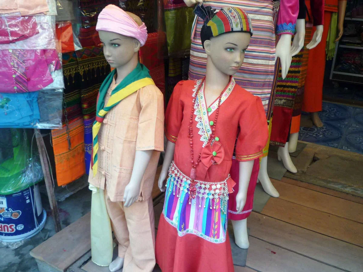 頭布や装飾のある色鮮やかな服を着せた二体のマネキンが店先に立っている