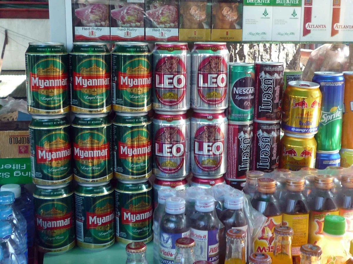 「Myanmar」「LEO」「Red Bull」「Sprite」などの缶飲料や瓶が店先に密集して並んでいる
