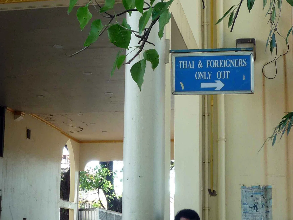 「THAI & FOREIGNERS ONLY OUT」と書かれ、右向きの矢印が付いた青い案内板