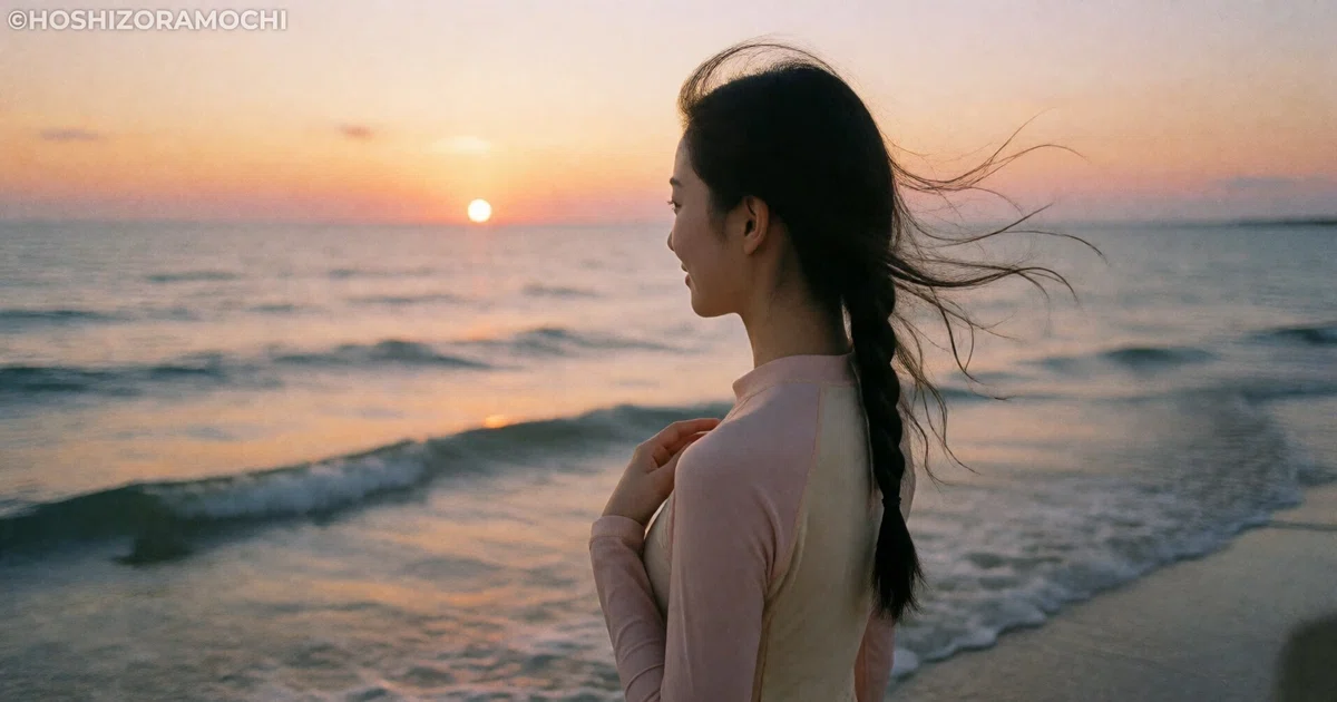 夕暮れの海辺に立つ女性の後ろ姿。