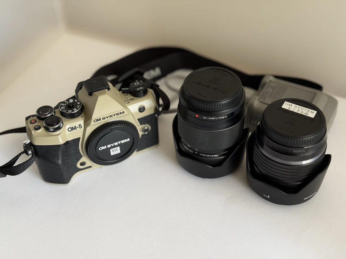 OM SYSTEMから借用したサンドベージュのOM-5 Mark II本体と、2本の交換レンズ、充電器、予備バッテリー