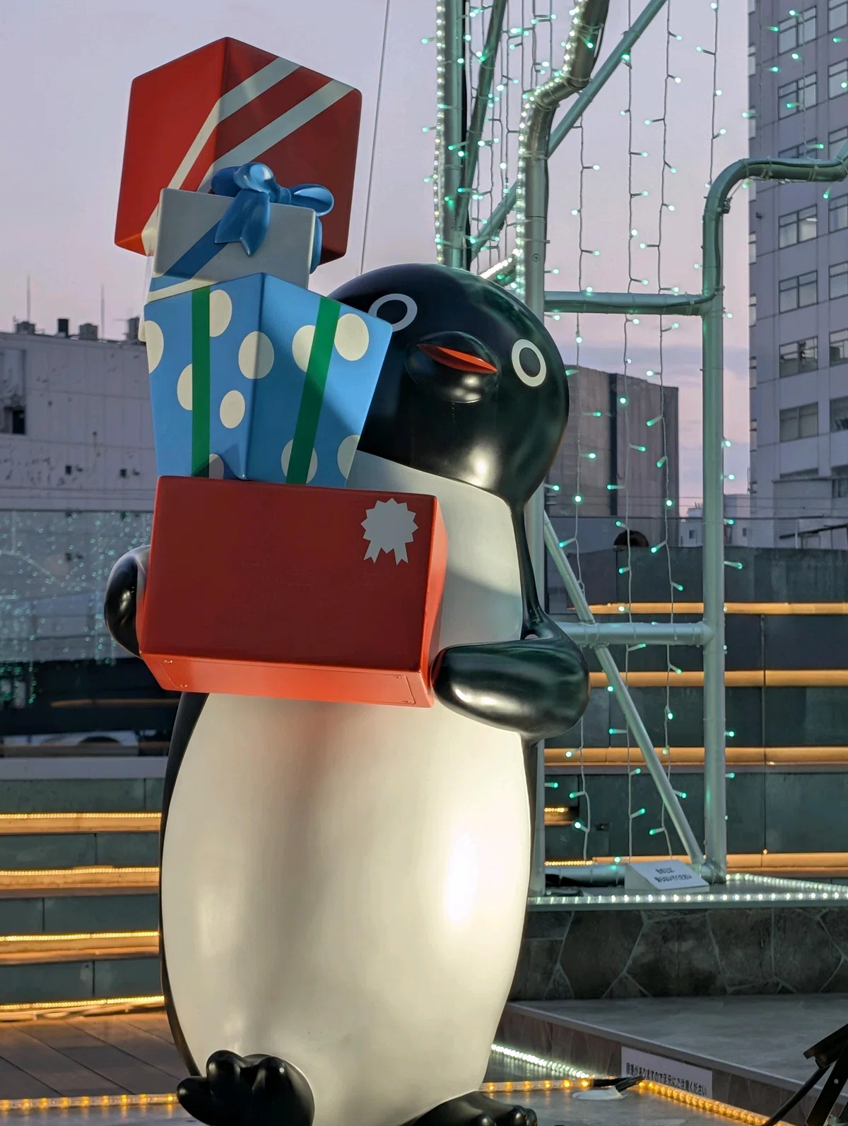 クリスマスシーズンの新宿イルミネーションの中で、色とりどりのプレゼントボックスをたくさん抱えているSuicaのペンギン像 Suicaのペンギンからクリスマスプレゼント