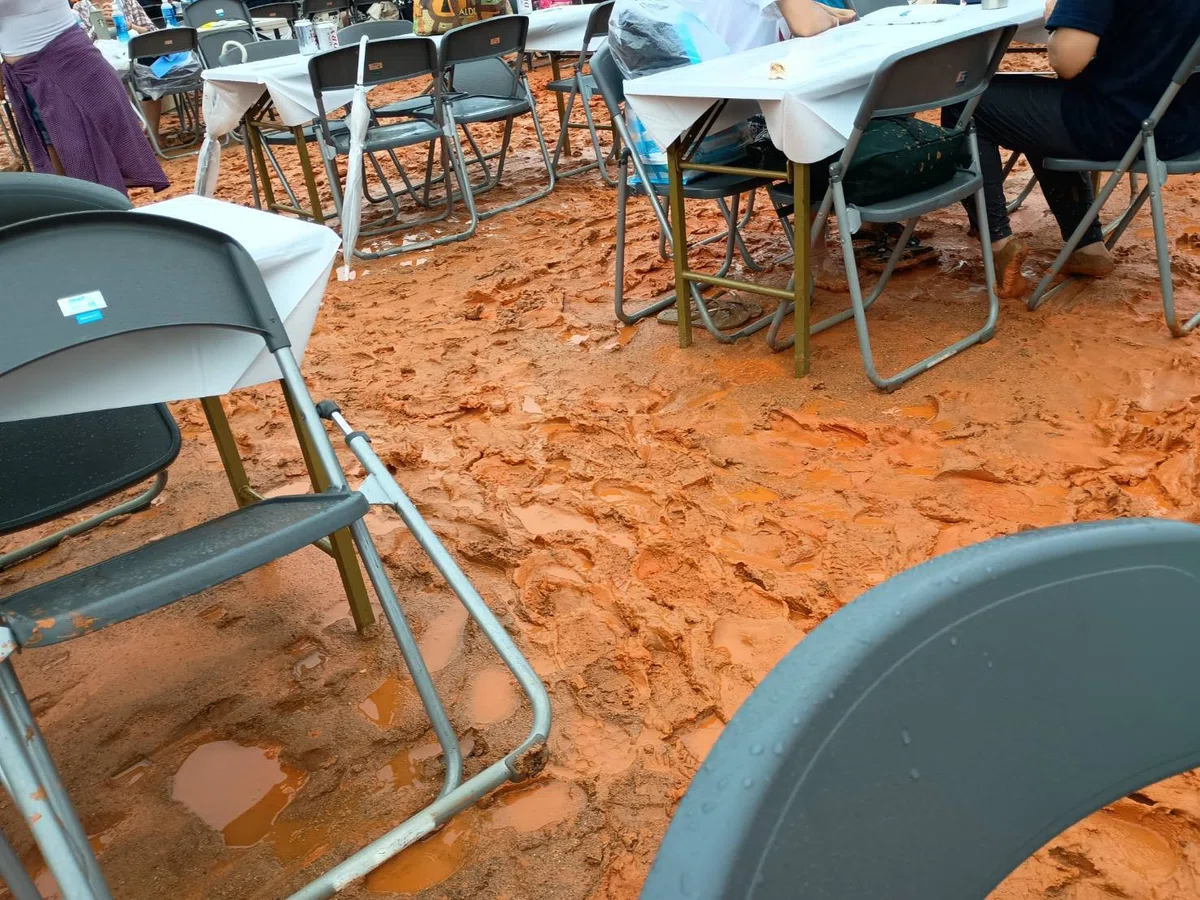 テーブルと椅子が並ぶ所で、赤土の地面がドロドロで、足跡がたくさんある