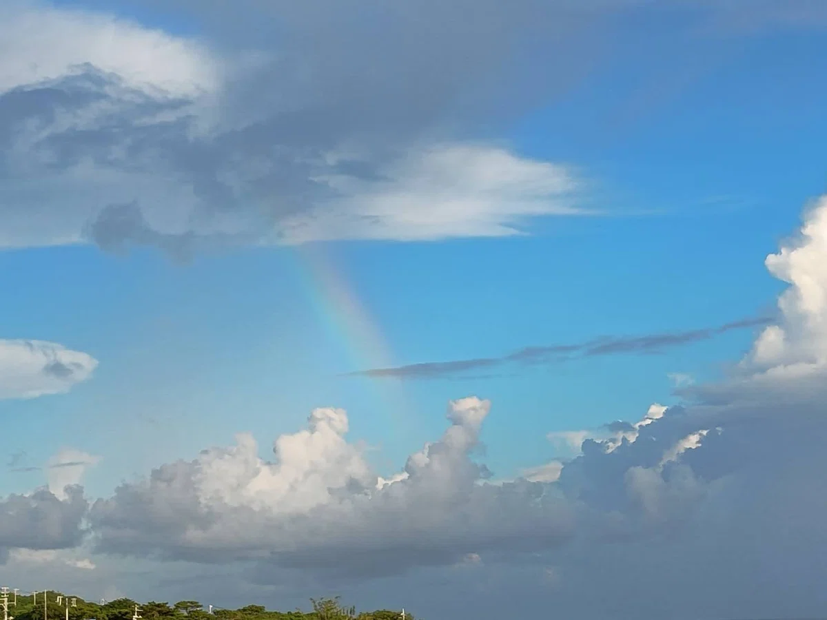 雲と雲の間に虹が出ている