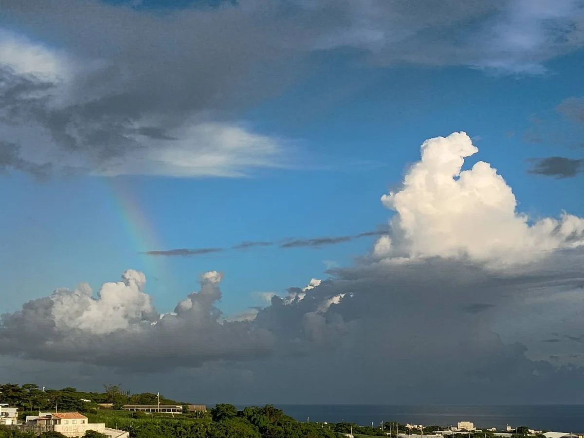 虹と隣には入道雲、下の方に民家と海