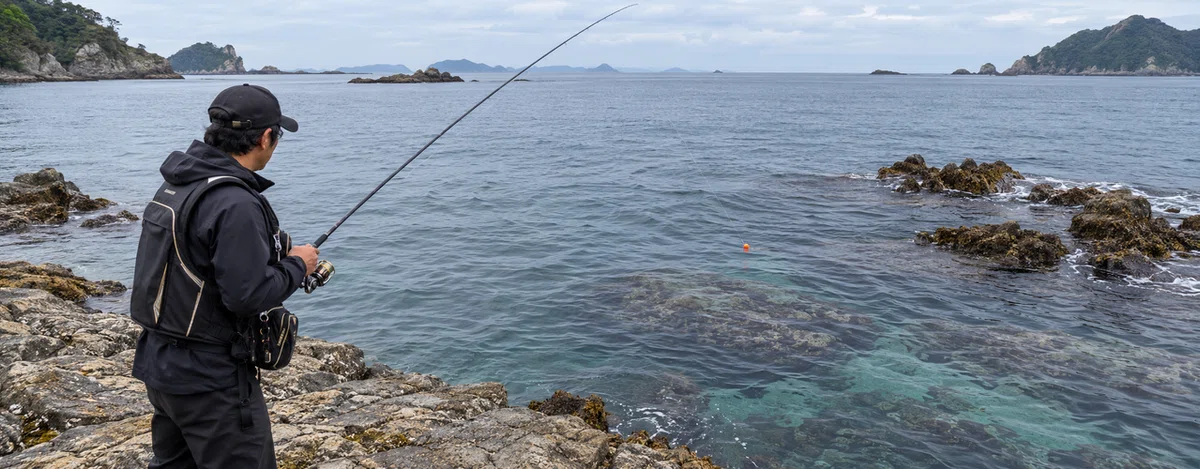 磯の流れに浮くウキを見ながら仕掛けを確かめる釣り人