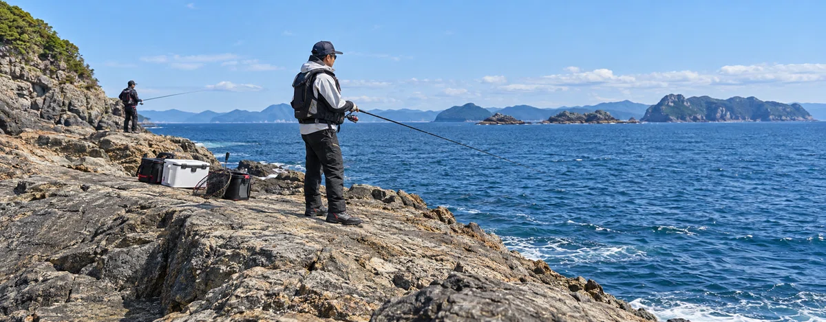 救命胴衣と磯靴を身につけ、広い岩場で釣る人たち