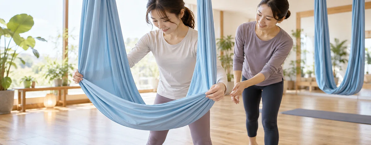 指導者のそばで青い布を両手で広げる参加者